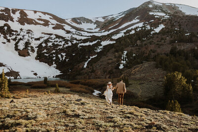 brride and groom running on a mountain