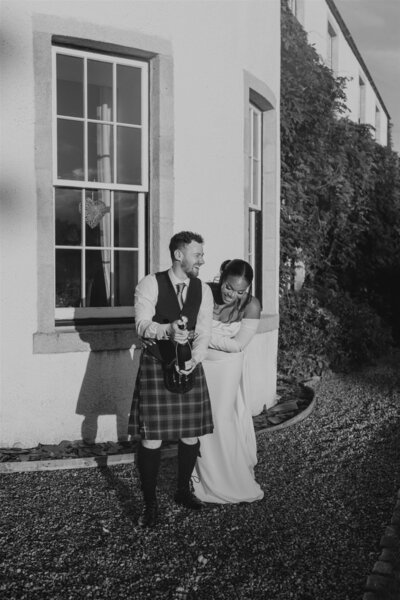 An LGBTQ+ couple candidly pose together for wedding photography as they walk down a country path. They walk hand in hand.
