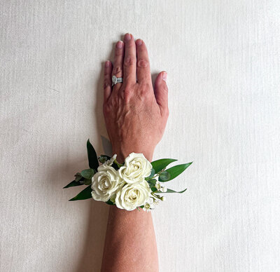 Wrist with a white floral corsage with greenery