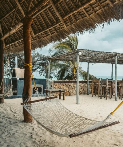 a peaceful hammock set up on a beach awaits your luxury vacation