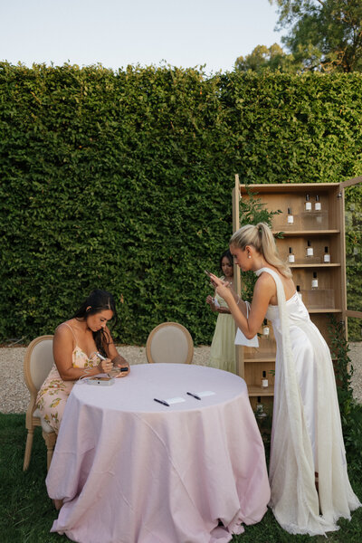 Hannah Godwin taking a photo of wedding calligrapher Cat Lauren creating custom wedding favors
