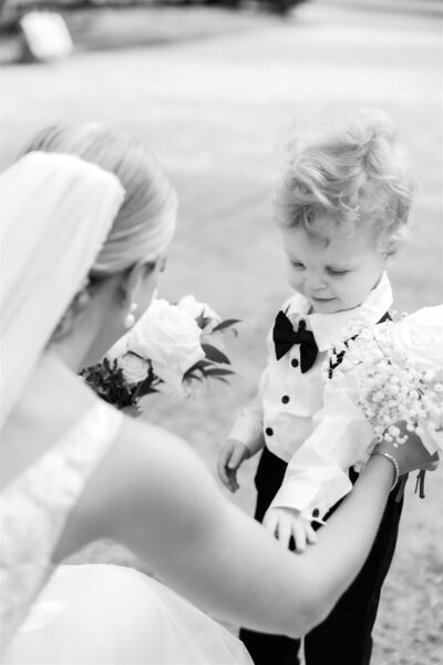 A tender moment between a Bride and the ring bearer in black and white 