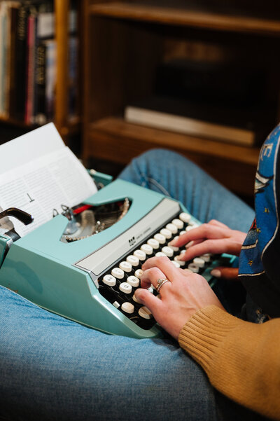 Close up image of Sarah Klongerbo's hands typing on a light blue typewriter