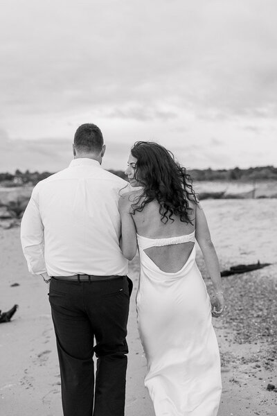The Corteses Newport Wedding Photographer and Videographer | Serving CT, RI, and beyond | Bride and groom belly button to belly button with bouquet around grooms neck with the ocean behind them