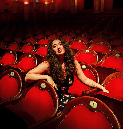 Photo portrait de la fondatrice du studio graphique indépendant Fenicia Studio, dans un opéra aux fauteuils rouges. 