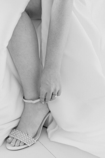 Bride buckling her shoes on her wedding day