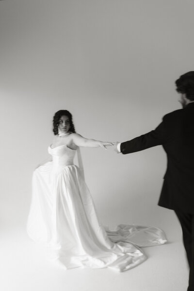 Bride and groom dancing together in a modern studio setting, captured by Rainstorm Photo & Video with an elegant, cinematic black and white style.