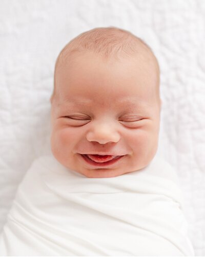 a newborn baby smiling with their eyes closed