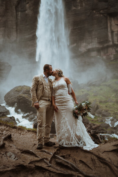 couple is standing at the base of a waterfall
