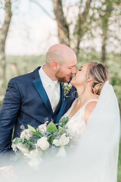 Bride and groom kissing outdoors on their wedding day, photographed by Zoe Evans Photography.