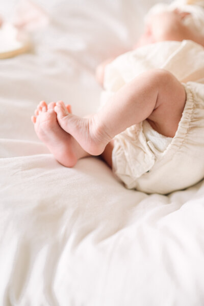 Close-up of a newborn baby’s tiny feet resting on soft white bedding, captured by a Northern Virginia family photographer during a newborn lifestyle session.