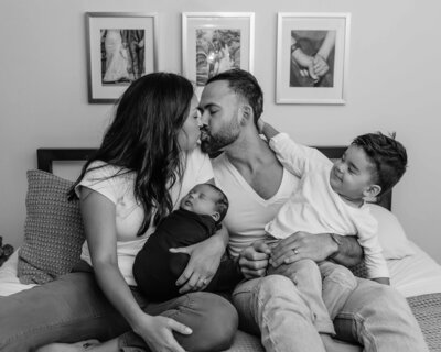Full family cuddled on bed during newborn session in Chicago, IL