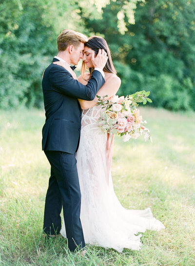 Bride and Groom Hugging Nose to Nose in Field Photo