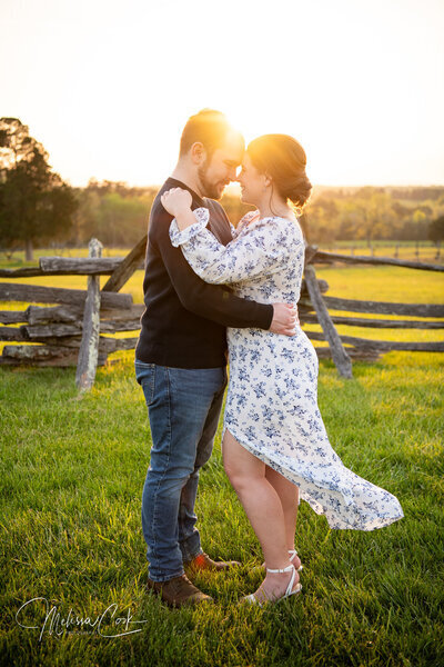 Couple hugs outdoors next to wooden fence in Leesburg VA engagement photos