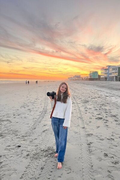 kylie on the beach , posing with her camera at sunset 