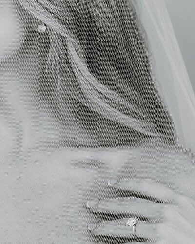 Rhode Island Wedding Photographers | Close-up black and white image of a woman’s bare shoulder with wavy hair, pearl earring, and a soft touch of her hand.
