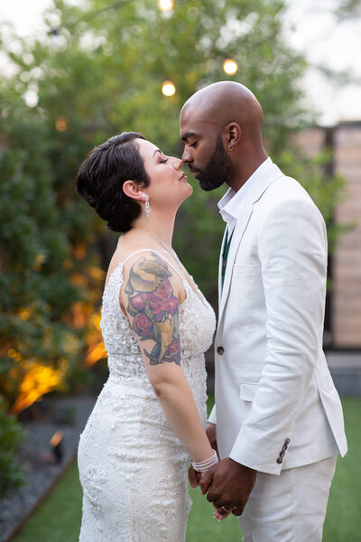 Austin-based wedding photographer captures a beautiful moment of a bride and groom sharing a passionate kiss in a serene garden setting.