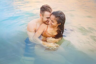 couple cuddling in the ocean at sunset in hawaii