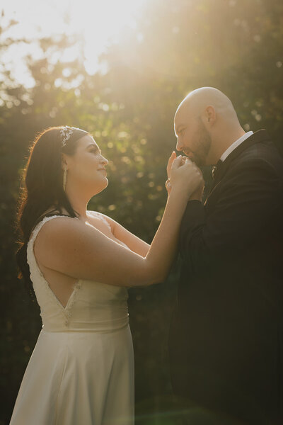 smiling couple kissing hand in sunlight