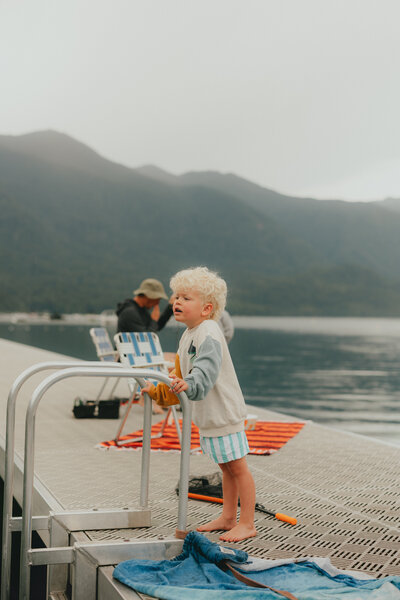 Photo of a little boy on a dock on the lake looking off camera too his mom taken by a langley photographer.
