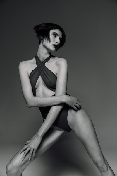 Black and white fashion portrait of short-haired model in bodysuit with striking pose