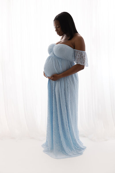 black mom wearing blue dress in studio by philadelphia maternity photographer