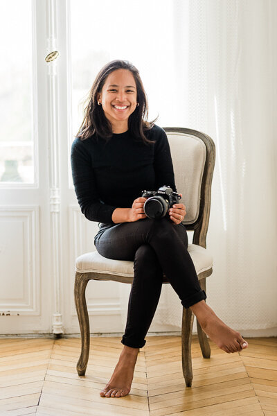 joanne rabenarisoa sitting on chair smiling at camera and holding camera