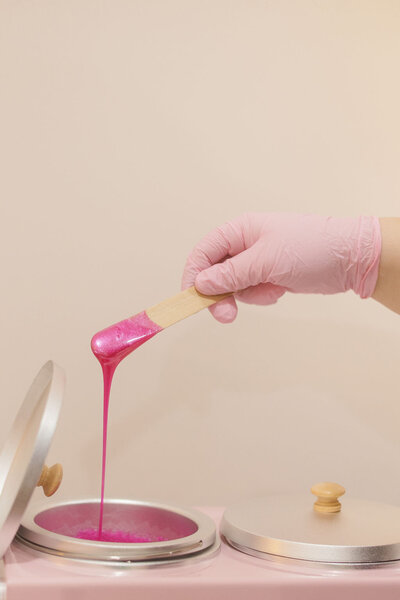 Wax stick over wax warmer during body waxing prep in Hartselle studio
