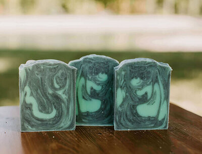 tea tree and activated charcoal goat milk soap for acne prone skin displayed on a table
