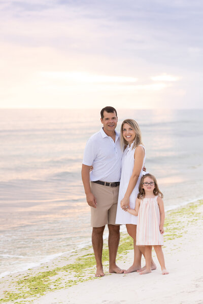 Two parents on the beach with the child smiling