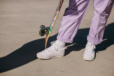 Close up of purple pants and a skateboard.