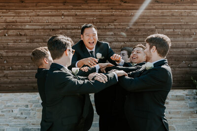 groomsmen throwing the groom in the air