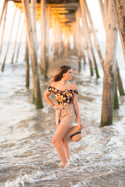 woman on the beach looking at the water under a doc