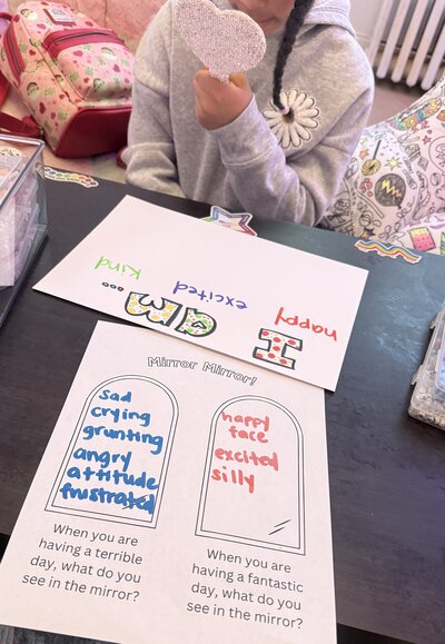Child looking into a handheld mirror completing an emotion identification exercise