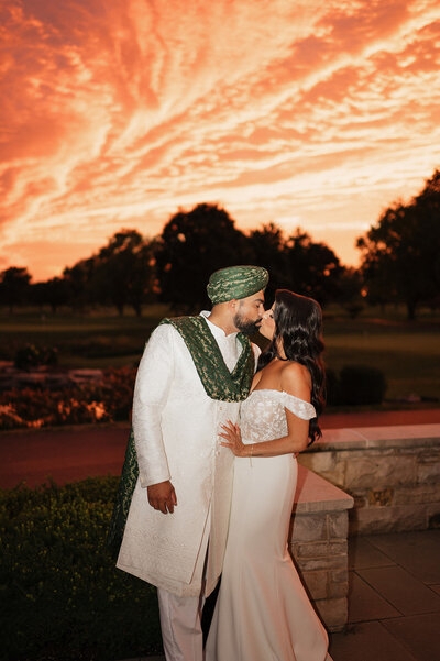 Bride and groom share a kiss at sunset on wedding day