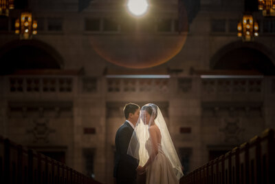 A blurred wedding couple walking at the base of a large staircase.