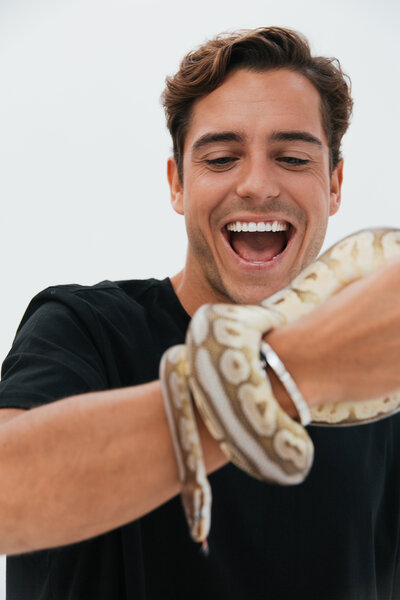 Playful and engaging portrait of a man interacting with a snake, part of the Gamechangers press shoot with floris gobel, captured by Bo Eppink.