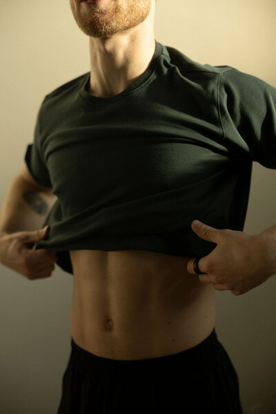 Client lifting their shirt to display toned abs, emphasizing great results powered by EMS training technology.