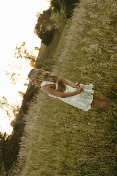 male senior in a prairie at sunset wearing a tan sweater
