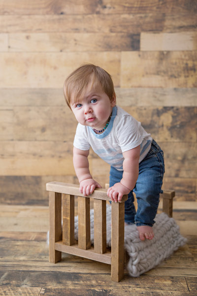 baby boy chubby cheeks standing on tiny bed