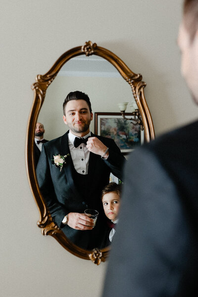 Marié se prépare en se regardant dans le miroir pour son mariage avec un enfant qui le regarde.