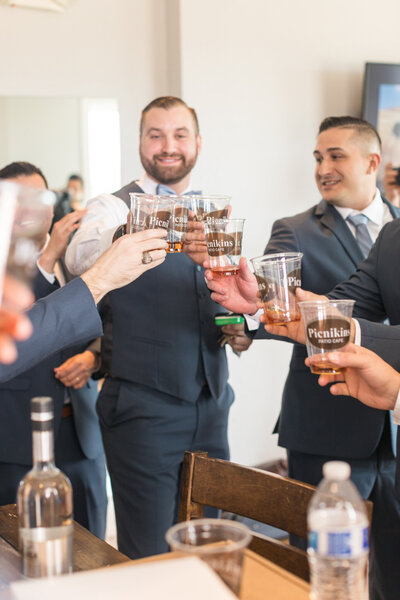 A groom and his groomsmen celebrate in the groom's suite.