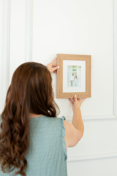 Jacqui of Heirloom Photo Collective hanging a portrait in a gallery wall