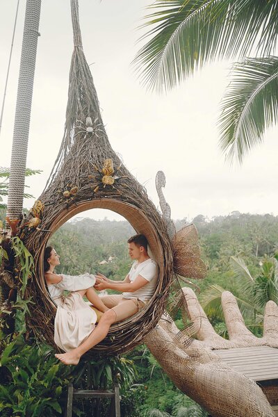 bride and groom sit in bamboo chair in bali