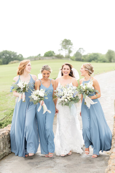 Bride and bridesmaid walk and laugh together.