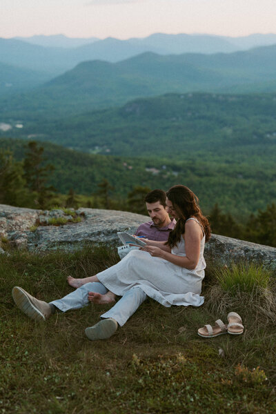 Couple snuggling together and doing a crossword puzzle during blue hour in New Hampshire.