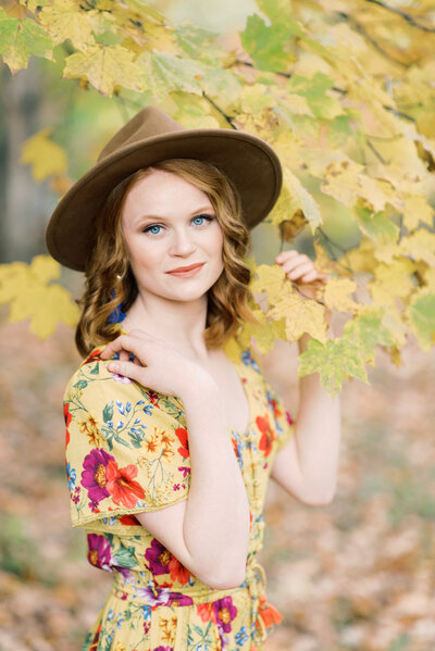 Senior girl with floral dress and hat smiling at the camera