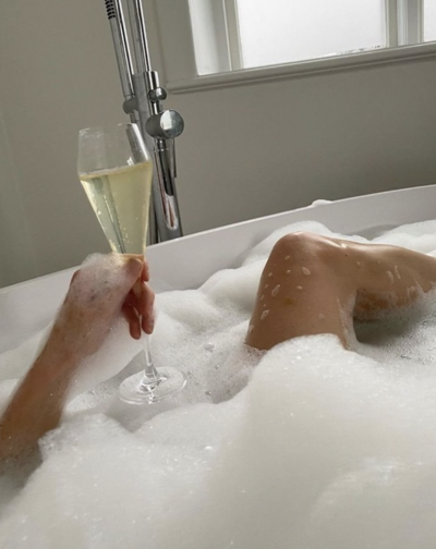 Image showcasing a relaxing bubble bath with a champagne glass, representing the tranquil atmosphere of Brave Beauty Spa, a Virginia Beach esthetician salon with a website design by The Aesthetic Edit.