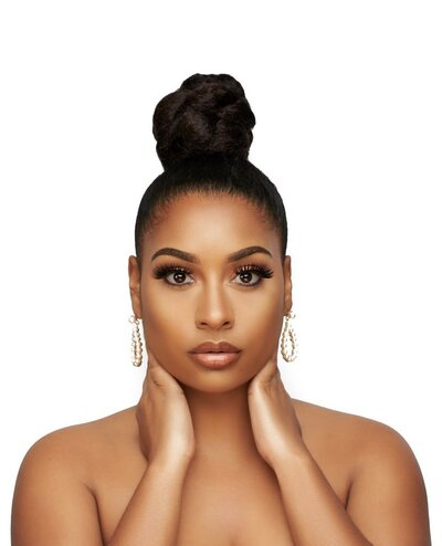 african american bride with top knot bun in natural glam makeup with hands on neck and in front of a white background