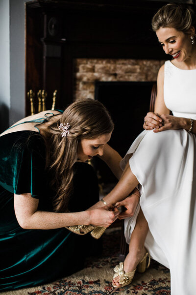 Bridesmaid putting on brides shoes